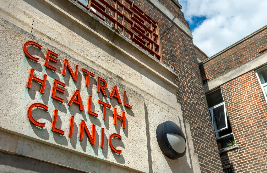 Image of the front entrance to red brick Central Health Clinic and the signage above the door reading \'Central Health Clinic\'
