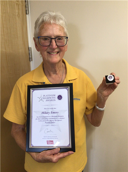 Volunteer Hilary Emery holds up her Queen's Platinum Jubliee award and certificate.