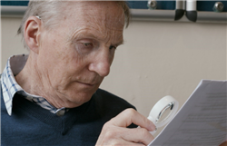 A man is using a magnifying glass to read a document