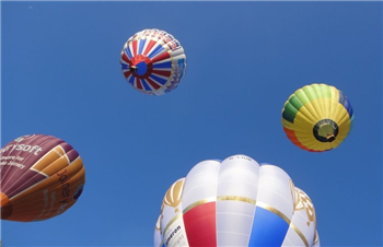 Hot air balloons rise into a clear blue sky at the Bristol Balloon Fiesta