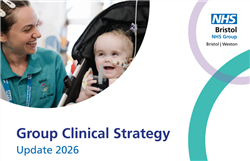 A member of the play team and a baby in a push chair laughing, next to Group Clinical Strategy 