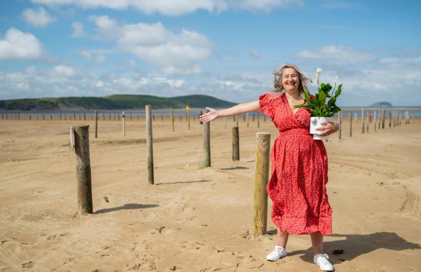 A woman is standing on the beach at Weston-super-Mare on a sunny day.