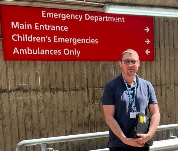 Alex standing outside the entrance to the emergency department