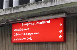 A red sign, outside the BRI building, which says Emergency Department. Main Entrance and Children's Emergencies have an arrow pointing right, Ambulance Only has an arrow pointing left